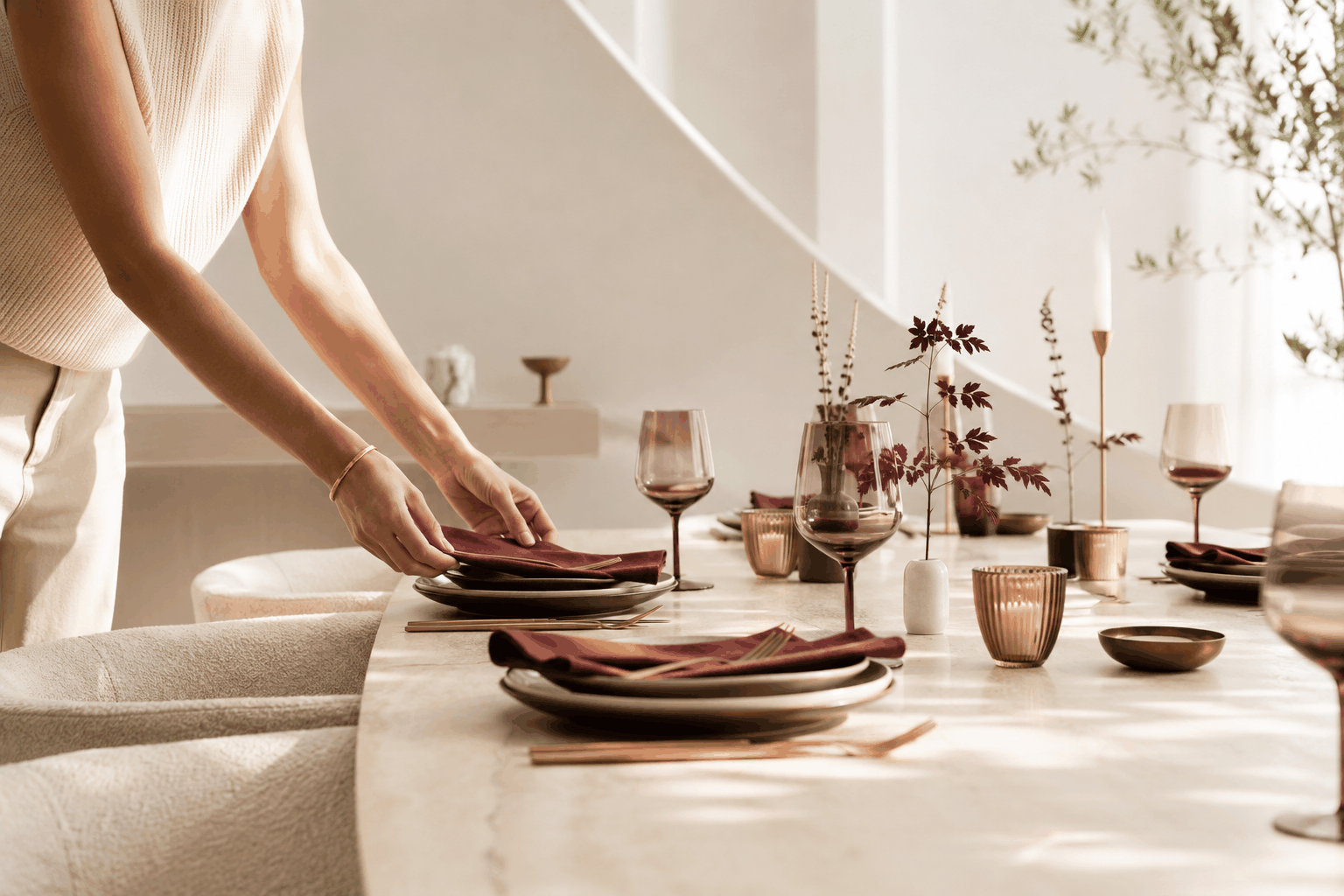 A table set with burgundy linens, brass flatware, and glassware.