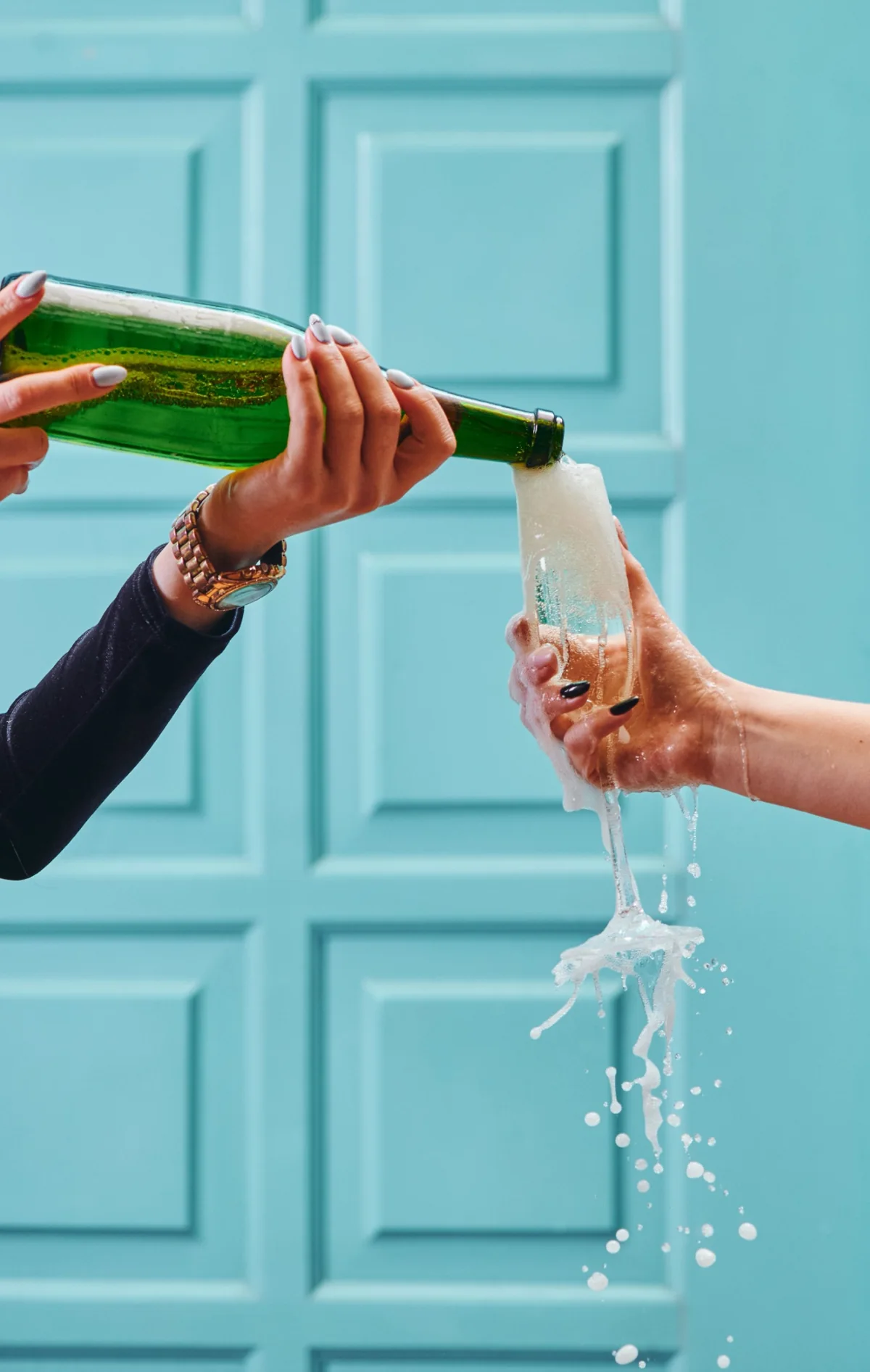 Champagne splashing into a glass in front of a blue doorway