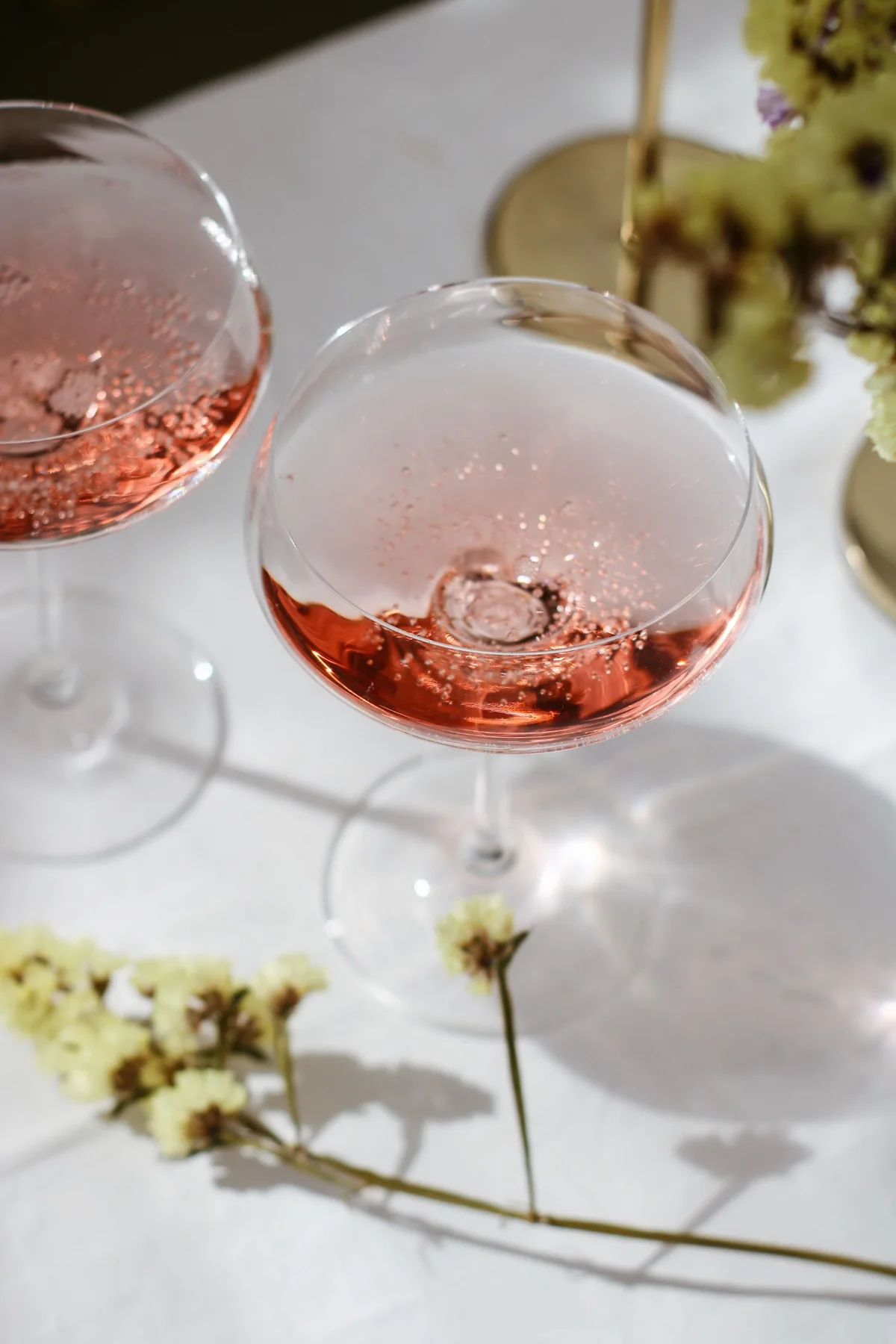 Pink drinks in coupe glasses on a sunlit table