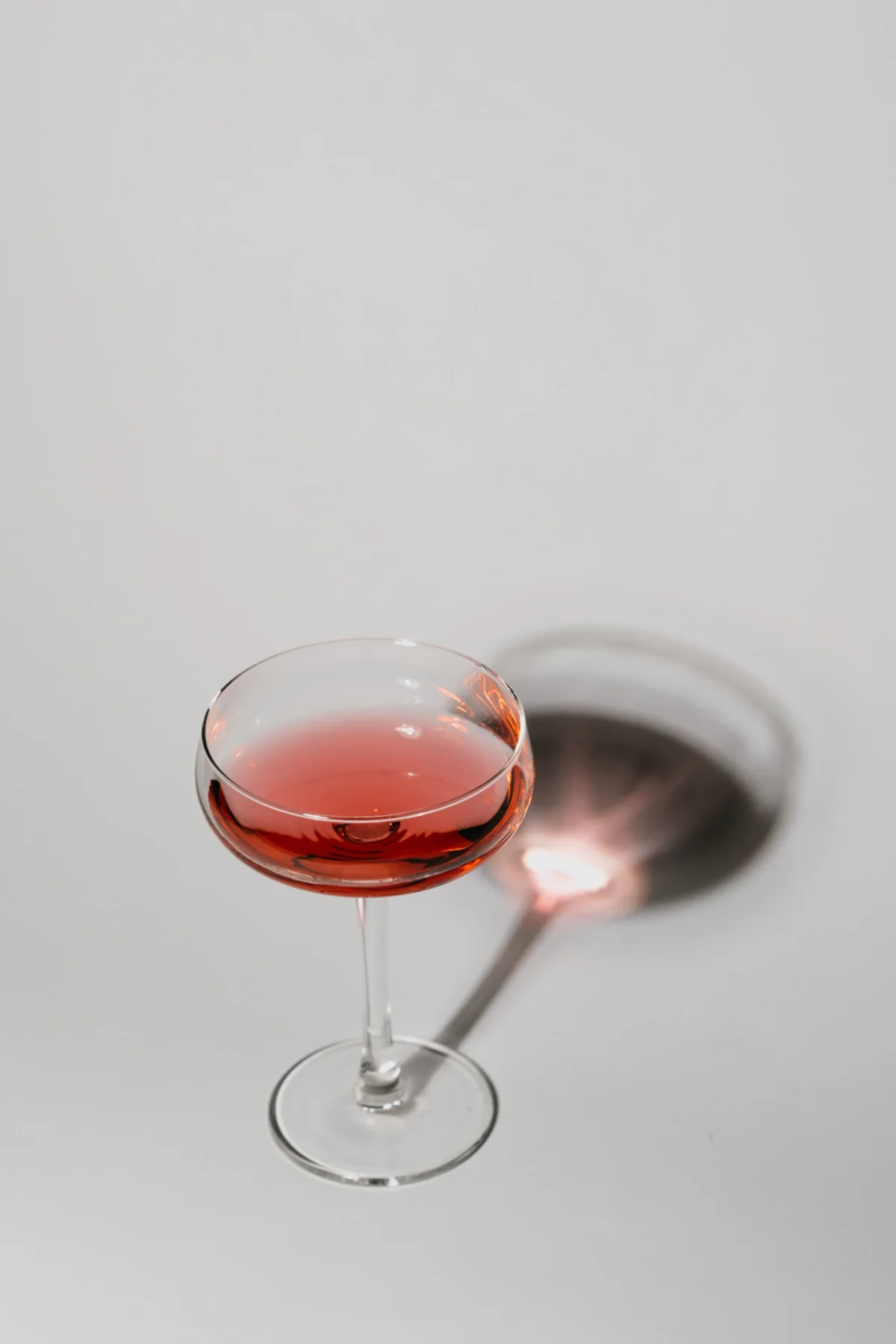 A single coupe with a long shadow on an ivory surface
